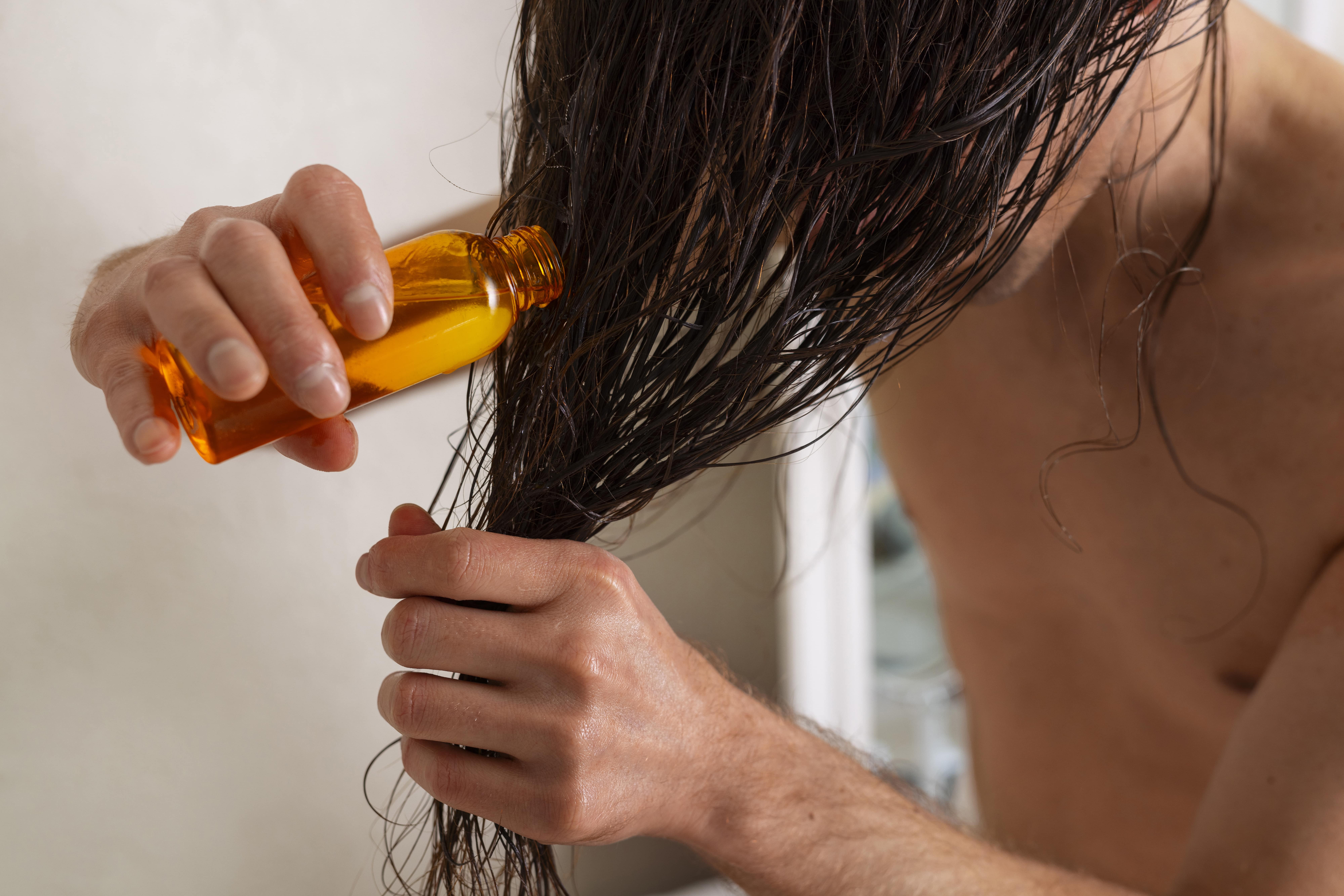 Male with wet hair using serum for hair growth Batana oil