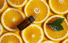 sliced oranges in background with essential oil in foreground