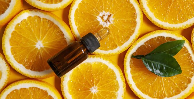 sliced oranges in background with essential oil in foreground