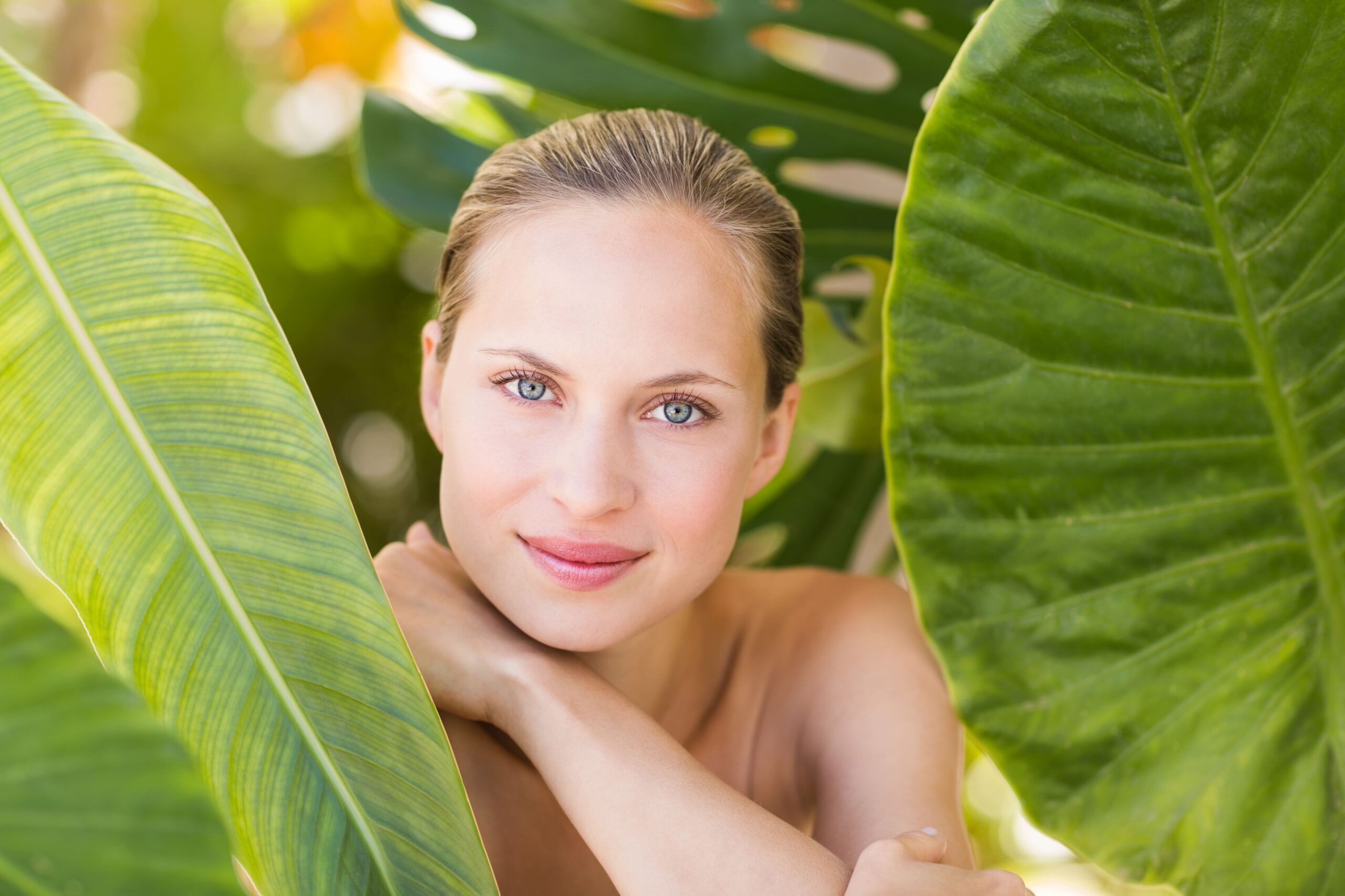 Young woman among leaves with beautiful smooth skin