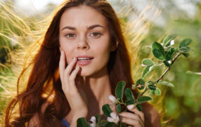 beautiful brown-haired lady in nature, holding a plant