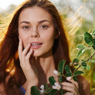 beautiful brown-haired lady in nature, holding a plant