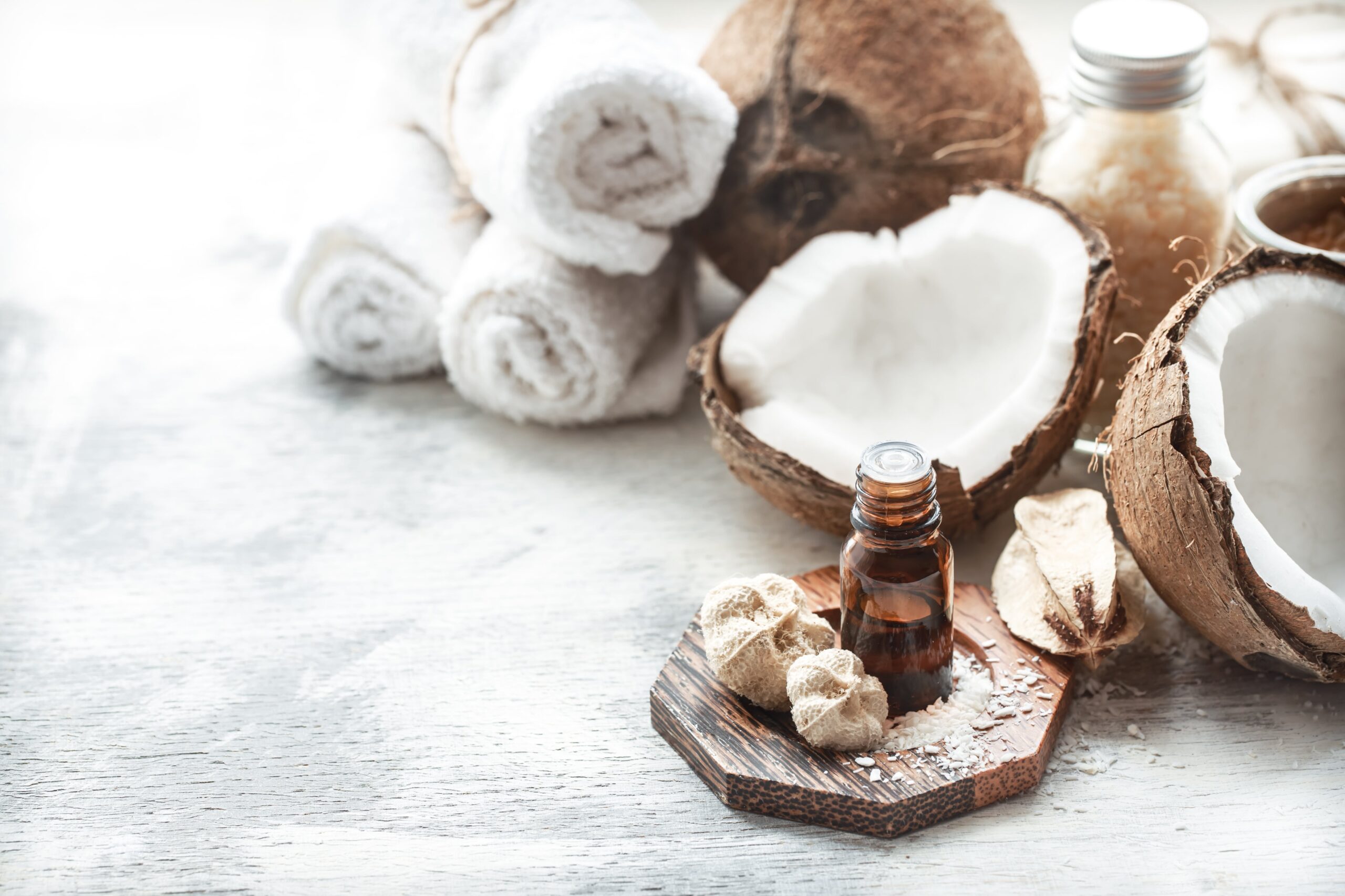 coconuts on marble background with brown oil bottle in foreground