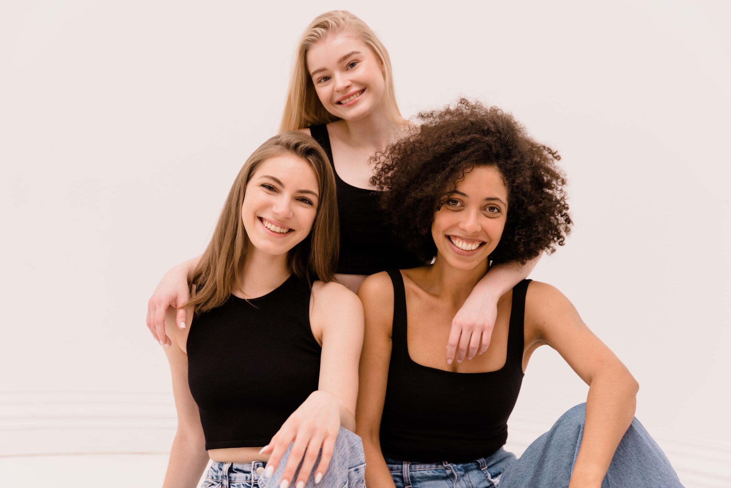 happy-young-interracial-beauty-girls-tops-jeans-smiling-looking-camera-white-background-min